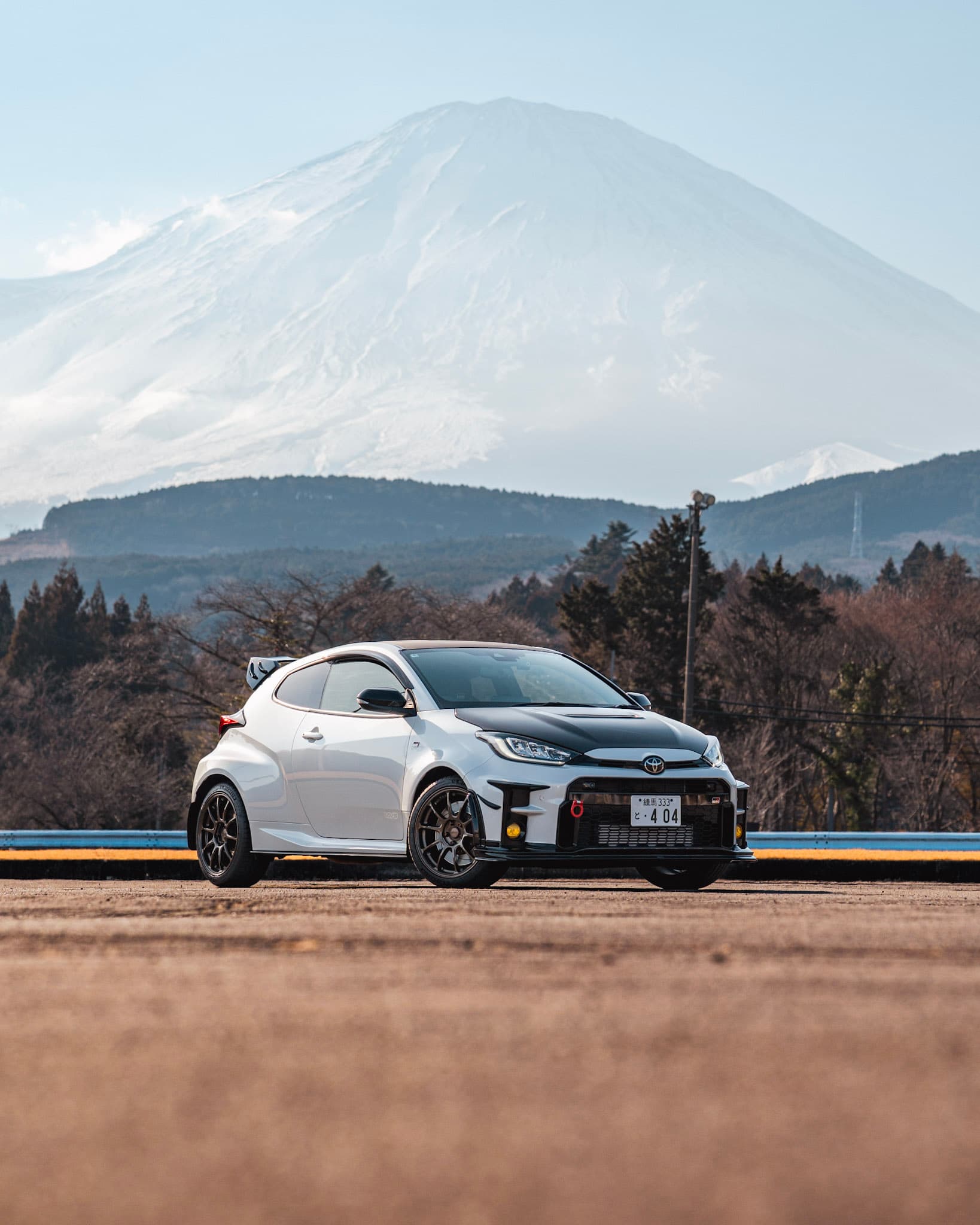 White Toyota GR Yaris parked against a snow-capped Mt. Fuji backdrop