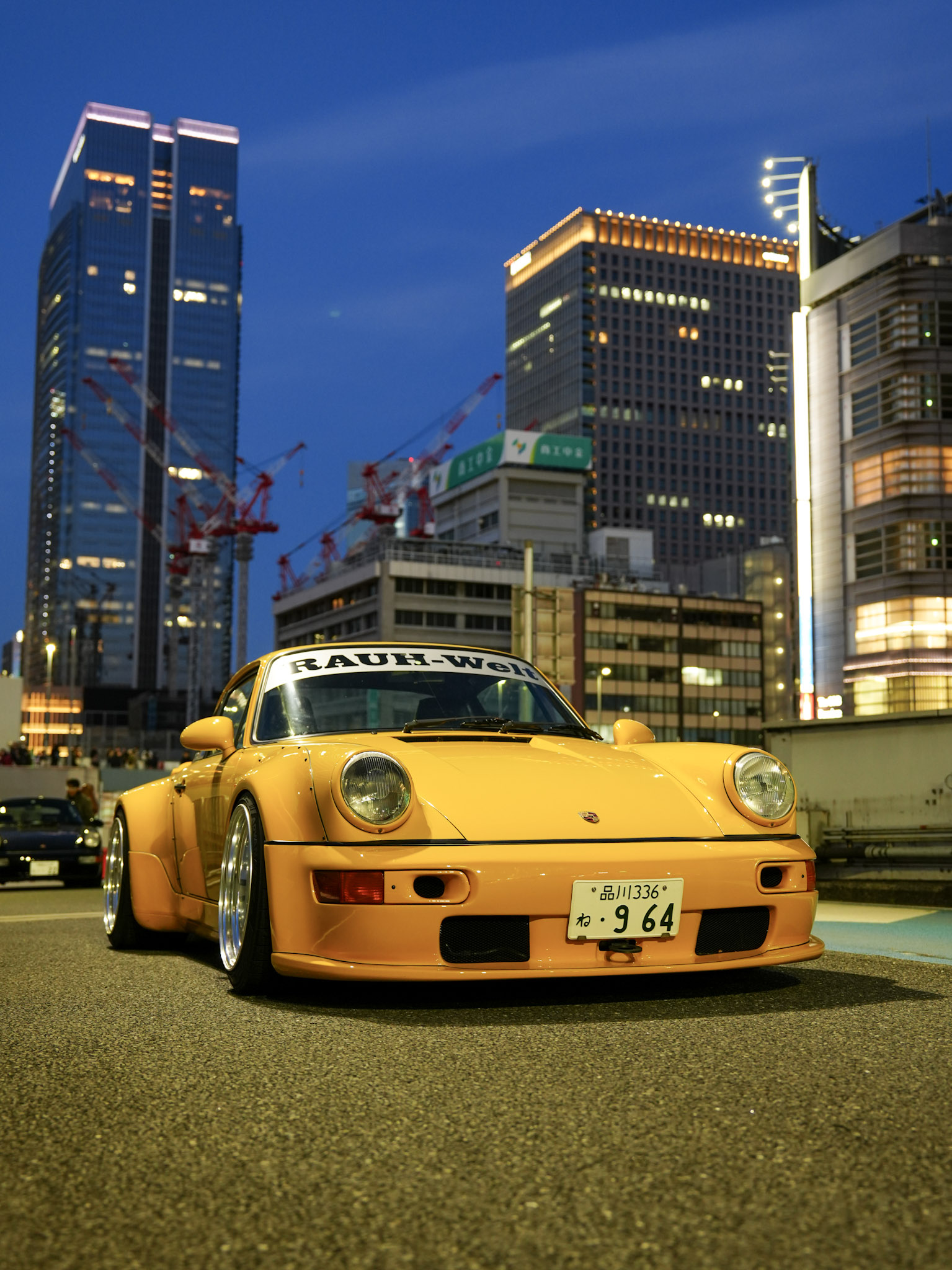 Yellow RWB Porsche 911 parked under blue-hour city lights in Tokyo